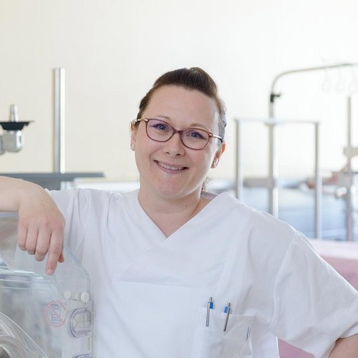 Pflegerin seht neben einem Inkubator